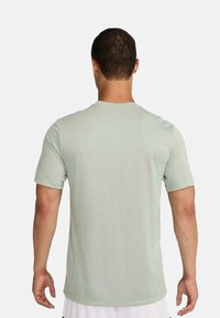 Camiseta de manga corta verde claro, hecha de una tela suave, con cuello redondo y un corte relajado, sin patrones ni acentos visibles.
