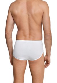 Hvide bomulds boxer briefs med blød tekstur og elastisk livrem, set fra bagsiden på en mandlig figur.