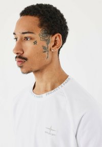 Camicia bianca a maniche corte con scollo rotondo, con la scritta "PROJECT X PARIS". Logo ricamato sottile sul petto, tessuto morbido.