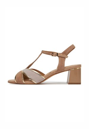 Beige suède sandaal met een T-band design, voorzien van metalen accenten en een blokhak. Gekruiste banden in lichte en donkere tinten.