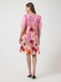 Blommönstrad kort klänning i rosa med puffärmar, prydd med flerfärgade broderade blommor. Genomskinligt tyg med rund halsringning.