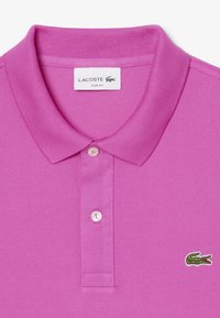 Rosa Lacoste polo shirt med en smal passform, texturerat tyg, ribbad krage och tvåknapplås. Har en liten grön krokodillogo.