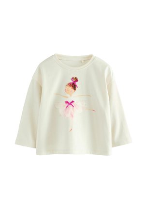 Kreemivärviline pikakä sleevesega beebipusa, mille ees on ballerina illustreerimine, kes kannab roosasid juuksekaunistusi ja tütarfriid.