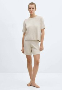 Beige knitted loungewear set featuring a short-sleeve top and shorts with a relaxed fit. Soft texture, simple design, and no visible patterns.