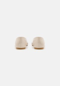 Beige lackleder Ballerinas mit runder Zehenpartie und niedriger, beigefarbener Sohle. Die glatte Oberfläche hat ein glänzendes Finish und dezente Steppnähte.