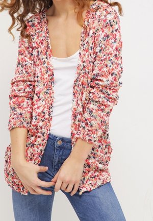 Cardigan en tricot avec un motif multicolore rouge, rose et blanc. Il a des manches longues, une ouverture devant et une coupe décontractée.