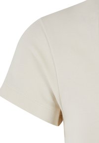 Manche courte en coton beige avec couture visible sur fond blanc uni.