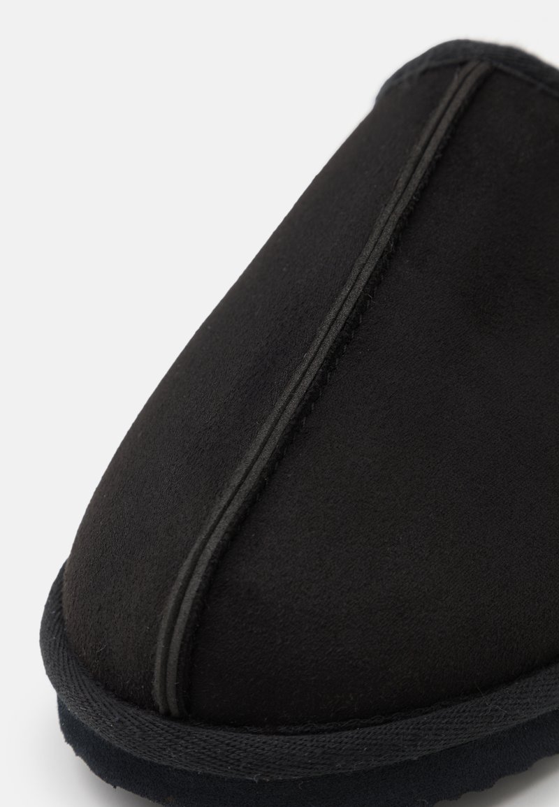 Pantofole nere con morbida superficie in suede, forma rotonda e cuciture a contrasto lungo il bordo, dotate di suola imbottita.