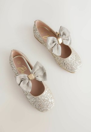 Kimaltelevat hopeanväriset balettitossut, joissa suuri hopeinen rusetti ja kultainen yksityiskohta. Sileä sisäpuoli ja pyöreä kärki.