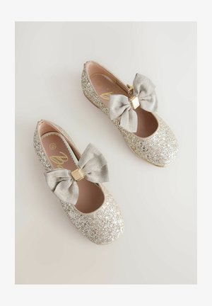 Ballerine argentate scintillanti con un grande fiocco argentato e dettaglio accentato in oro. Interno liscio e design con punta arrotondata.