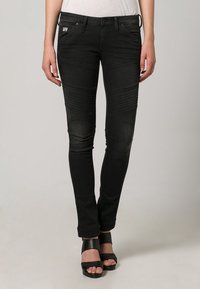 Jeans skinny de denim negro con acentos de textura acanalada en los muslos y las rodillas, que cuentan con cinco bolsillos y una cinturilla de altura media.