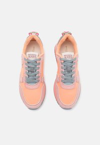 Roze en grijze sneakers met een gestructureerde bovenkant, voorzien van een zachte voering, contrasterende veters en een kleurrijk label op de hiel.