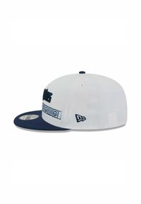 Weißes Baseballcap mit navyblauem Schild, mit gestickten Buchstaben auf der Vorderseite und Logo an der Seite. Glatte Stofftextur.