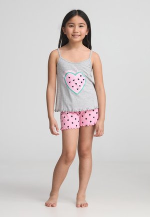 Canottiera grigia con una grafica a forma di cuore e pantaloni corti rosa con cuori neri. Entrambi hanno bordi ondulati, realizzati in un tessuto morbido.