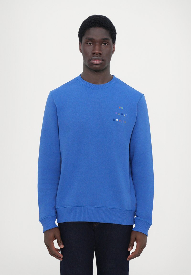 Sweatshirt en coton bleu avec un col rond, des poignets et un ourlet côtelés. Présente un logo en texte multicolore sur la zone gauche de la poitrine.