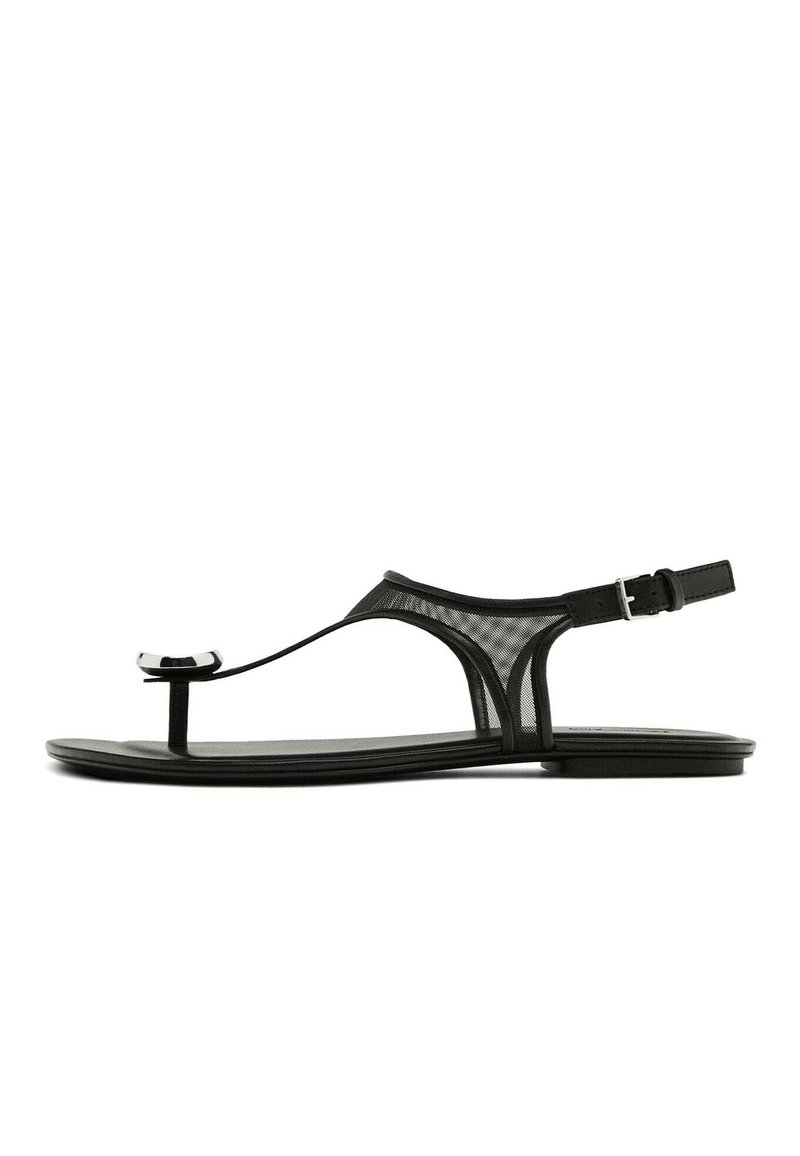 Černé ploché sandály s síťovým páskem, tenkým prstovým kroužkem a nastavitelnou sponou na kotníku. Mají elegantní, minimalistický design s lesklými akcenty.
