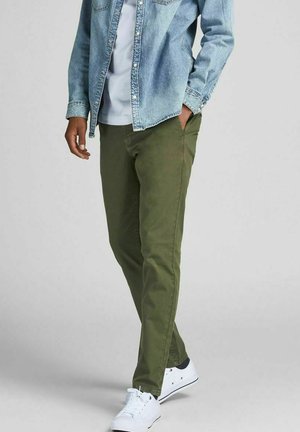 Chinos verde oliva in cotone, con vestibilità slim e tasche laterali. Abbinati a una camicia in denim chiaro con bottoni e sneakers bianche.