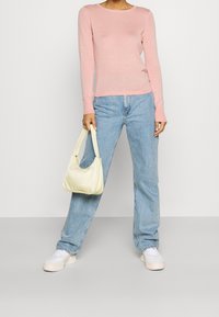Ljusrosa långärmad topp, i kombination med ljusblå högmidjade jeans. Off-white handväska och vita sneakers med texturerade sulor.