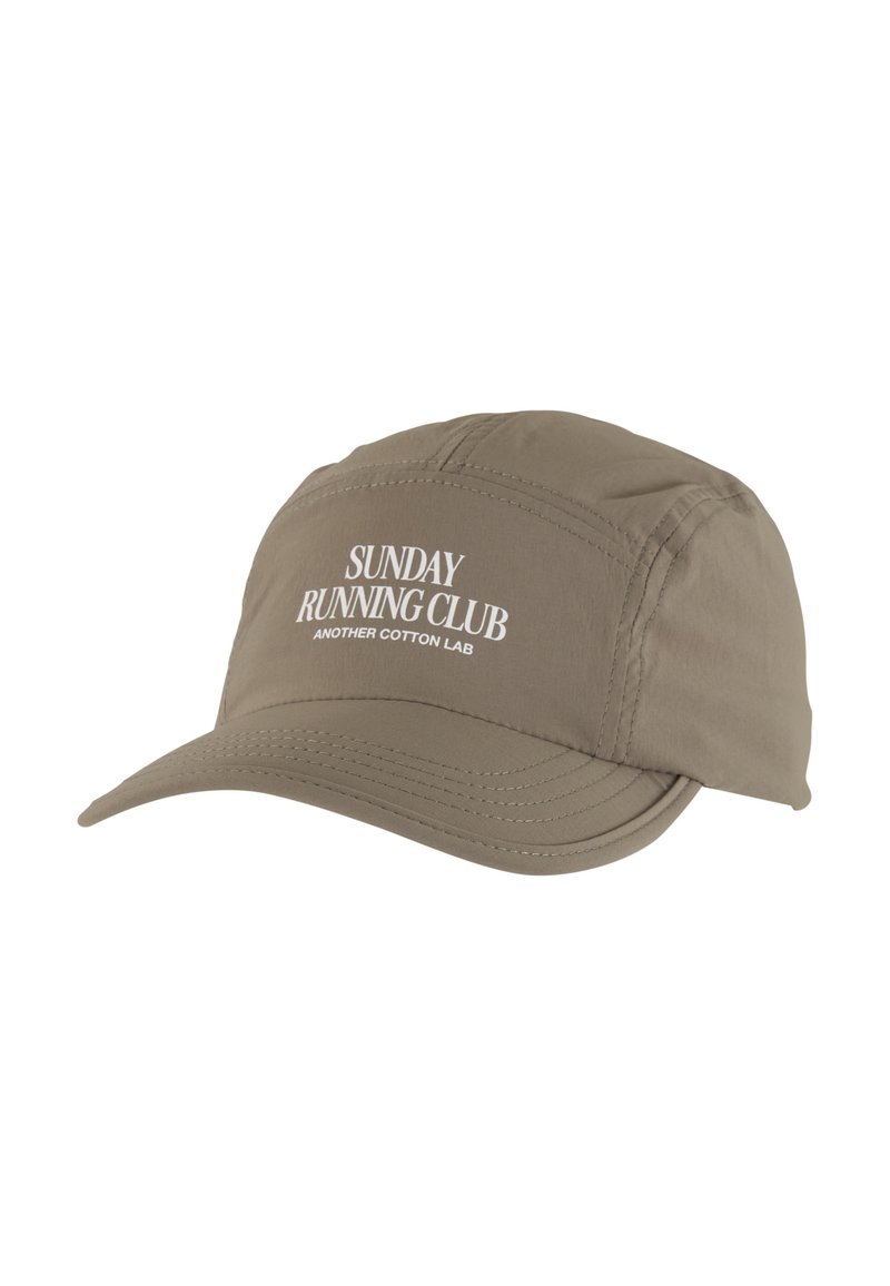 Lys brun løpecaps med buet skjerm, med hvit tekst "SUNDAY RUNNING CLUB" og "ANOTHER COTTON LAB" brodert på forsiden.