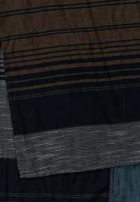 Tissu textile présentant des rayures horizontales bleu foncé, marron et gris de largeurs et textures variées, mettant en valeur des motifs tissés et des finitions.