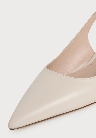Gros plan sur une chaussure slingback à bout pointu couleur crème, avec une finition en cuir lisse et une doublure intérieure beige.