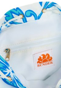 Borsa con cordoncino con interni bianchi, dotata di una tasca con zip. Esterno decorato con motivi blu e turchesi. Logo SUNDEK visibile.