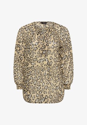 Blouse imprimé léopard beige avec des taches noires et marron, présentant un col à cordon et de longues manches bouffantes. Texture soyeuse.