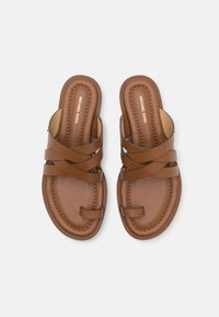 Brown leather sandals with crisscross straps, padded footbed, and gold logo detail. Smooth texture and round toe design for comfort.