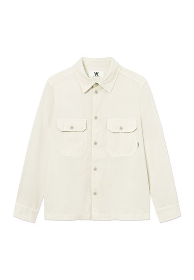 Chemise à manches longues de couleur blanc cassé avec boutons, deux poches à rabat sur le devant et un col classique, posée à plat sur un fond blanc.
