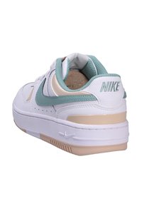 Nike tenisky v bílé barvě s mátově zelenými a béžovými akcenty. Vyznačují se koženým svrškem, síťovaným jazykem a texturovanou gumovou podrážkou.