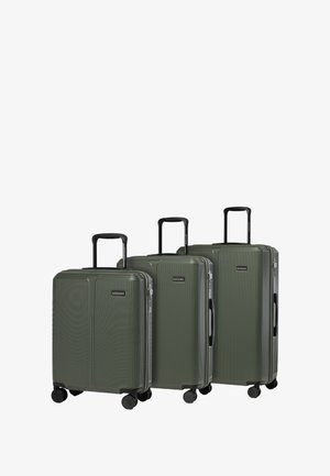Conjunto de tres maletas verdes rígidas con estrías verticales, asas negras y ruedas. Presenta un detalle de logo en la parte frontal.