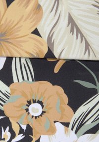 Bloemenstof met grote gele en oranje bloemen met groene accenten op een donkere achtergrond, met een textuur en geweven afwerking.