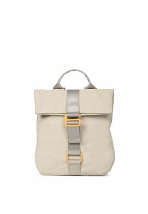 Mochila de tela beige con un asa superior, solapa plegable y una correa central gris asegurada con dos hebillas naranjas.