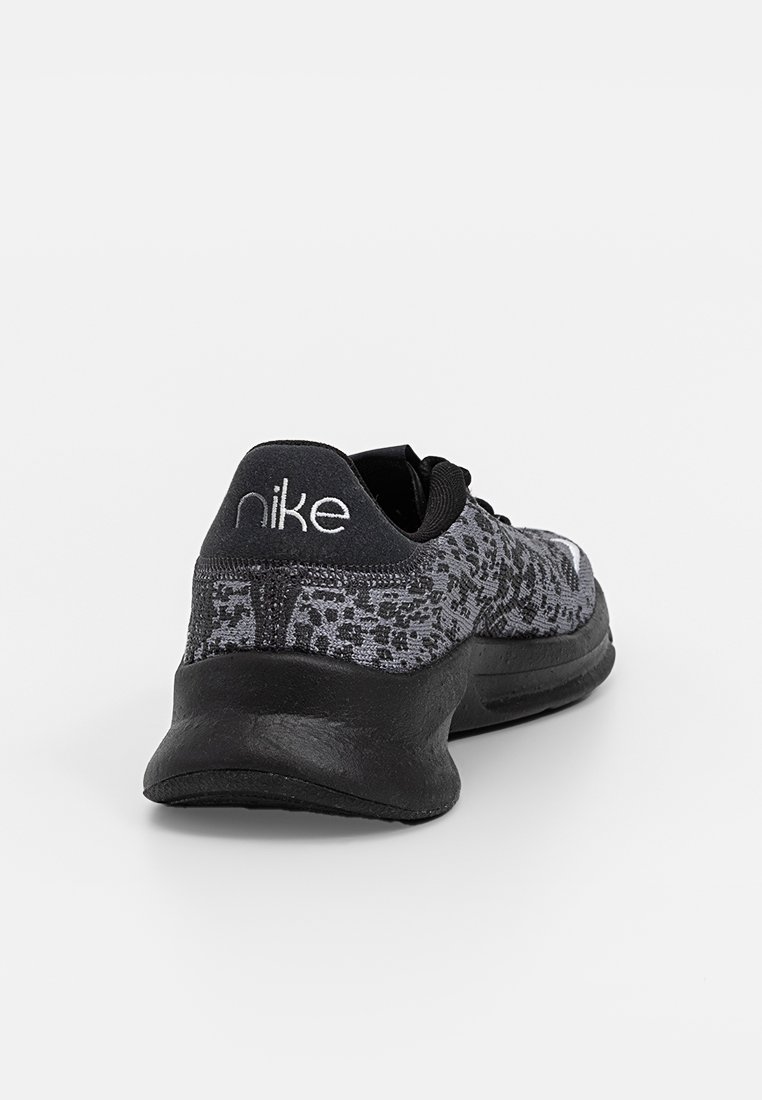 Zapatilla deportiva Nike en material de punto negro y gris con patrón texturizado, que presenta un collar acolchado y una suela gruesa negra.