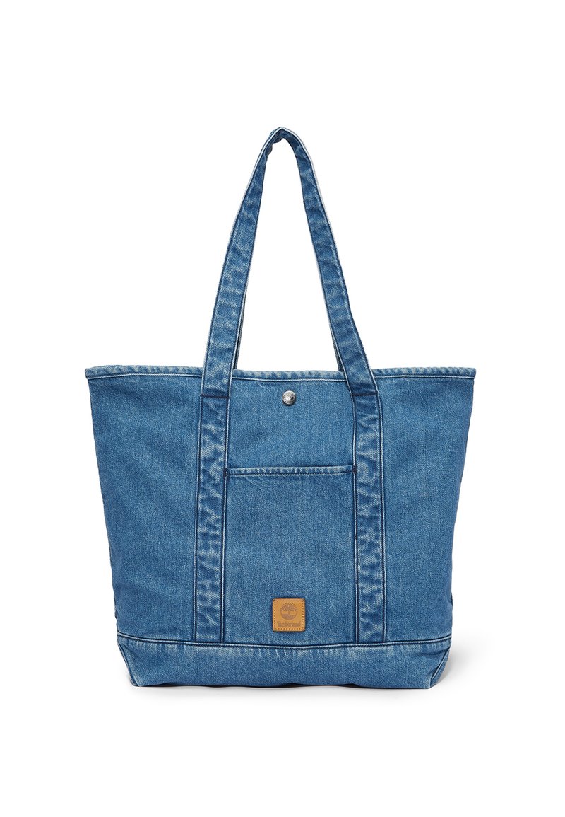Blå denim totebag med lange håndtag, frontlomme med trykknap og Timberland-logo-patch på lommen.