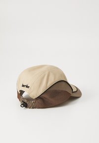 Casquette beige avec visière courbée, dos en maille marron et bande élastique. Présente des coutures foncées et un logo minimaliste sur le côté.