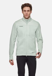 Mintgrüne Softshelljacke mit hohem Kragen, Reißverschluss vorne und zwei Seitentaschen. Sie verfügt über ein schlankes, tailliertes Design und ein Logodetail.