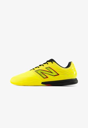 Gelbe Sportschuhe mit schwarzen Akzenten. Verfügen über ein strukturiertes Obermaterial, Perforationen für Atmungsaktivität und eine Gummisohle für besseren Halt.