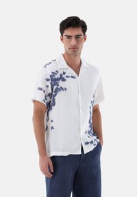 Weißes Kurzarmhemd mit blauem Blättermuster, Knopfleiste und lässiger Passform. Hergestellt aus leichtem Stoff.