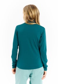 Dlhý rukáv top vo farbe teal, vyrobený z mäkkej a elastickej tkaniny. Obsahuje zakrivený lem a priliehajúce rukávy, navrhnuté pre pohodlie a všestrannosť.