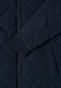 Giacca trapuntata blu navy con zip frontale, motivo a diamante testurizzato e dettagli in costina sui polsini. Materiale liscio e leggero.