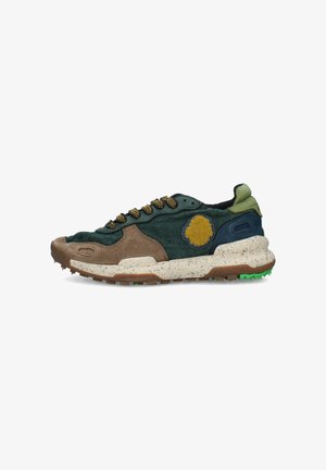 Sneaker bassa verde, marrone e blu navy con toppa circolare gialla, suola bianca maculata e lacci verdi e gialli fantasia.