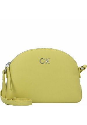 Borsa a tracolla gialla in pelle con una silhouette arrotondata, chiusura con zip e hardware in argento, caratterizzata dalle lettere "CK" impresse sul davanti.
