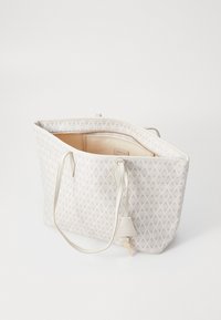 Light grey tote bag with a textured geometric pattern, twin shoulder straps, and an open top, revealing a beige interior with a label.