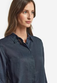 Navyblå linneskjorta med krage som kan knäppas, med en mjuk textur och en subtil lyster, designad för en avslappnad passform.