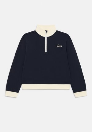 Mörkblå tröja med vita mudd, nederkant, hög krage, halvmatchande dragkedja och texten "Perfekt Outfit" på bröstet.