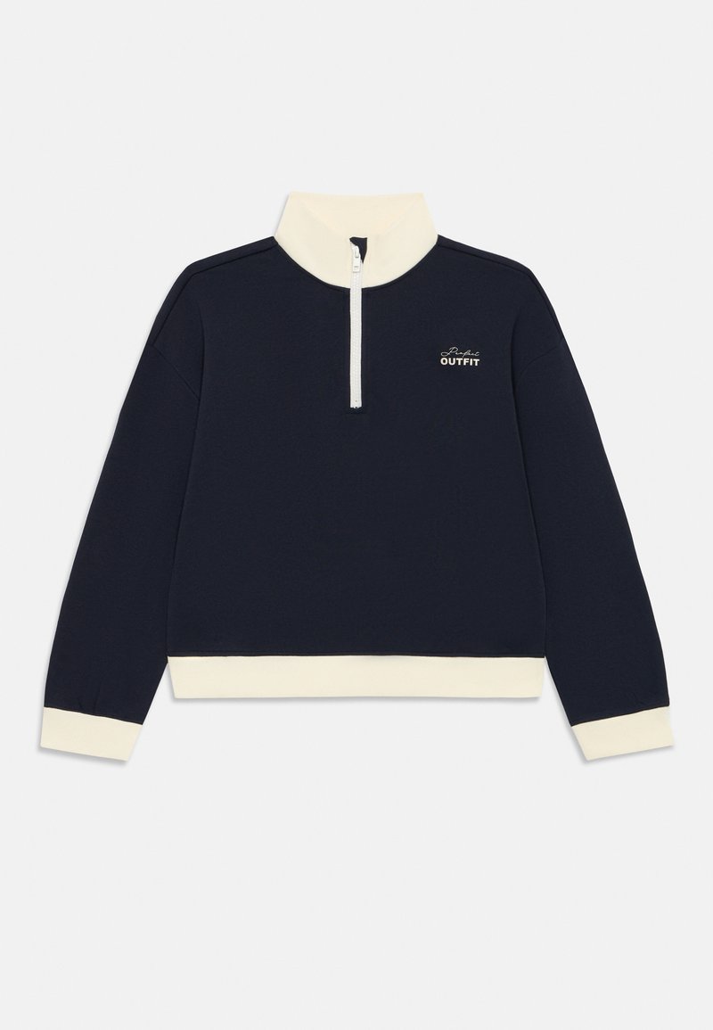 Tummansininen villapaita, jossa valkoiset hihat, helma, korkea kaulus, puoli vetoketju ja "Perfect Outfit" -teksti rinnassa.