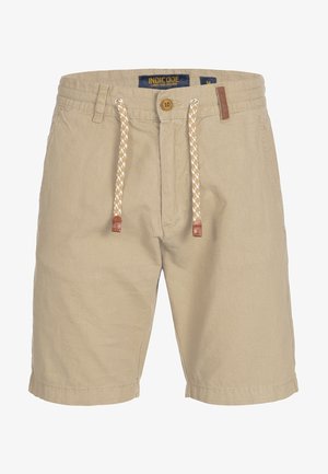 Shorts beiges en tissu léger, avec une fermeture à bouton, un cordon de serrage à texture imprimée et une petite étiquette en cuir sur la taille.