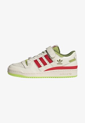 Baskets basses Adidas blanches avec des rayures rouges, intérieur et semelle verts, laçage devant et une sangle velcro au-dessus des lacets.