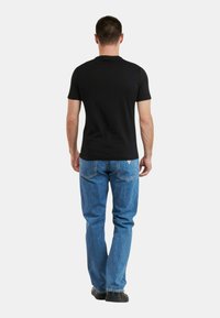 Camiseta negra de manga corta combinada con jeans de mezclilla azules. Los jeans tienen un corte recto, dos bolsillos traseros y un estilo informal.